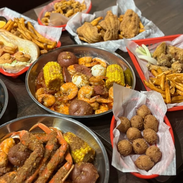 A feast of The Pirate's Boil seafood, including crab legs, shrimp, corn, potatoes, and fried sides.