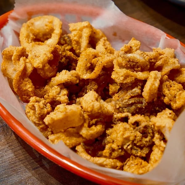 Close-up of crispy fried calamari in a red basket lined with white paper.